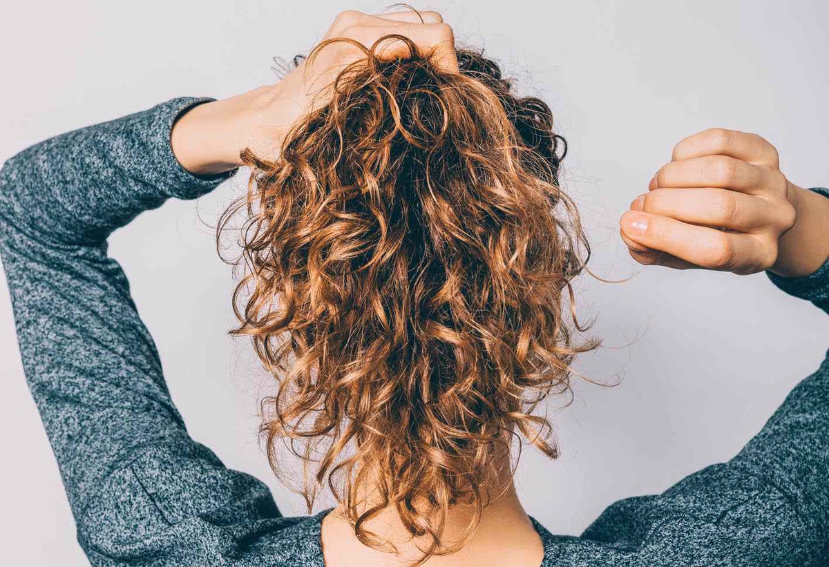 How can you effectively manage frizzy hair for a smoother appearance?